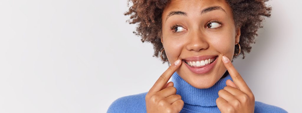 A woman smiles confidently after porcelain veneer treatment, showing the cosmetic result La Costa Dental Excellence patients in Carlsbad, CA achieve