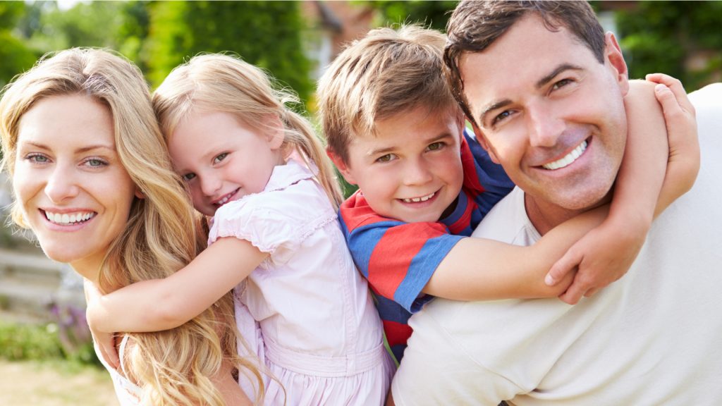 young family smiling after receiving teeth cleanings at family dentistry